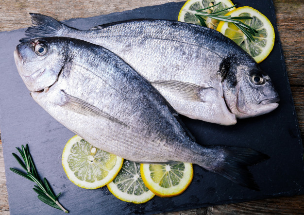 pescado-fresco-limon-tablero-rustico_144627-24523